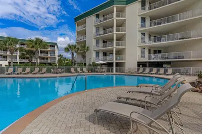 a swimming pool with lounge chairs in front of a building at Beautiful 2nd-floor condo in Seagrove Beach with beach ambience & pickleball in Santa Rosa Beach