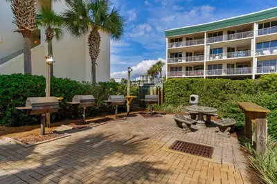 a patio with benches and picnic tables in front of a building at Beautiful 2nd-floor condo in Seagrove Beach with beach ambience & pickleball in Santa Rosa Beach