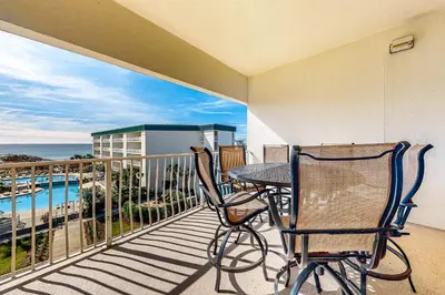a balcony with a table and chairs and the ocean at Lovely home with pool & Gulf views covered parking bikes & pickleball in Santa Rosa Beach