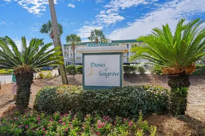 a sign in front of a hotel with palm trees at Lovely home with pool & Gulf views covered parking bikes & pickleball in Santa Rosa Beach
