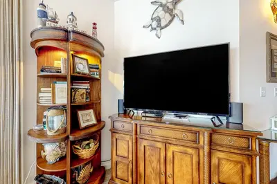 a television on a wooden entertainment center in a living room at Lovely home with pool & Gulf views covered parking bikes & pickleball in Santa Rosa Beach