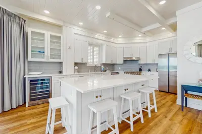 a kitchen with white cabinets and a large island with stools at Gulf-front view & spacious condo with wraparound balcony & pickleball in Santa Rosa Beach