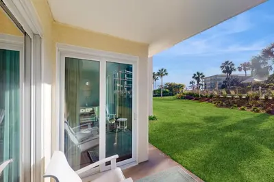 a sliding glass door of a house with a yard at Beachfront condo with 2 beach chairs included & pickleball - short walk to dining in Seacrest