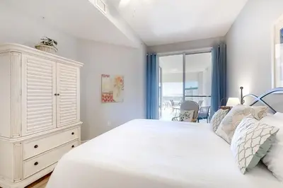 a white bedroom with a large bed and a window at Magical 3rd-floor condo with pools telescope for stargazing & pickleball in Santa Rosa Beach