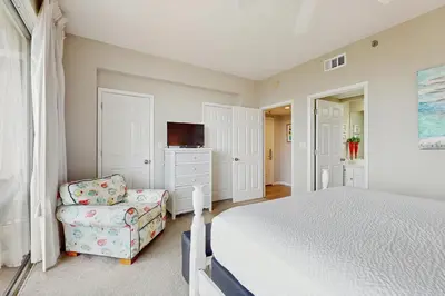 a bedroom with a bed and a chair at Snowbird-friendly condo with pickleball on the beach close to shops & dining in Seacrest