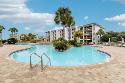 a large swimming pool in front of a building at Snowbird-friendly condo with pickleball on the beach close to shops & dining in Seacrest