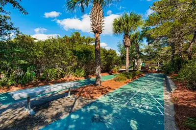 a swimming pool with two palm trees and a bench at Snowbird-friendly condo with pickleball on the beach close to shops & dining in Seacrest