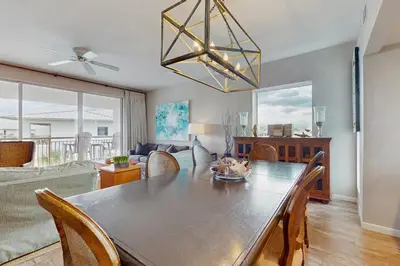 a dining room with a table and a living room at Snowbird-friendly condo with pickleball on the beach close to shops & dining in Seacrest