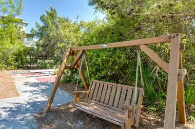 a swinging bench in a park with trees at Condo on the beach with tennis pickleball shuffleboard & balcony in Seacrest