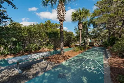 a pathway with two palm trees and a bench at Condo on the beach with tennis pickleball shuffleboard & balcony in Seacrest