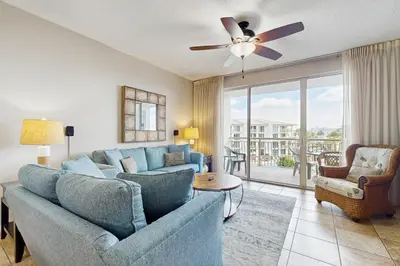 a living room with a blue couch and a ceiling fan at Elegant abode overlooking the pool with beach access tennis & pickleball in Seacrest