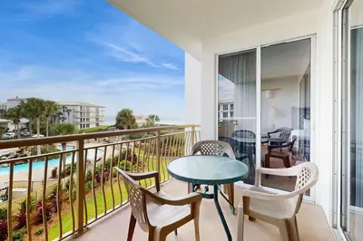 a balcony with a table and chairs and a view of the ocean at Elegant abode overlooking the pool with beach access tennis & pickleball in Seacrest