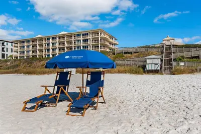 two blue chairs and an umbrella on a beach at Elegant abode overlooking the pool with beach access tennis & pickleball in Seacrest