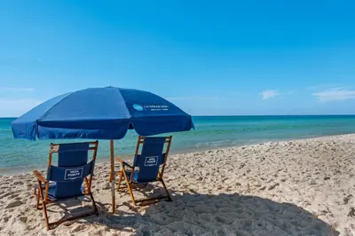 two chairs and an umbrella on a beach at Elegant abode overlooking the pool with beach access tennis & pickleball in Seacrest