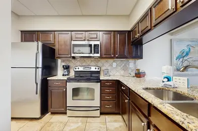 a kitchen with stainless steel appliances and wooden cabinets at Elegant abode overlooking the pool with beach access tennis & pickleball in Seacrest