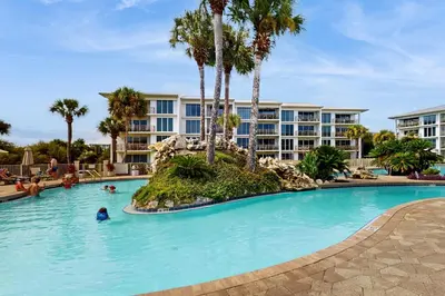 a pool at a resort with people in the water at Gorgeous home with tennis pickleball pool & hot tub - steps from the beach in Seacrest