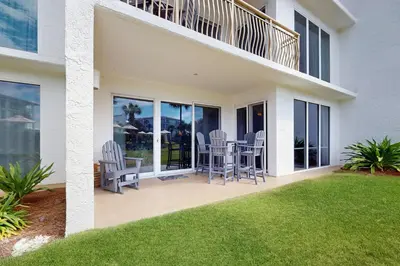 a patio with chairs and a balcony at Gorgeous home with tennis pickleball pool & hot tub - steps from the beach in Seacrest