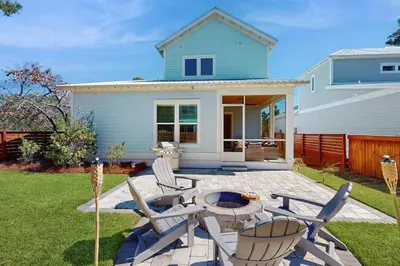 a patio with chairs and a table in front of a house at Sleek beach-themed retreat with patio bikes LSV & pool access in Inlet Beach