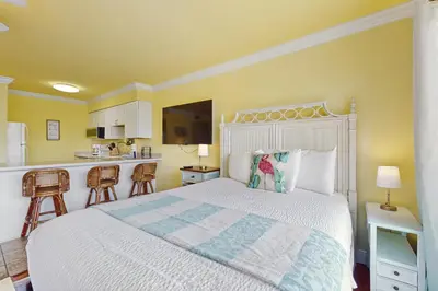 a bedroom with a white bed and a kitchen at Beachview studio with full kitchen shared pool and beach access in Santa Rosa Beach