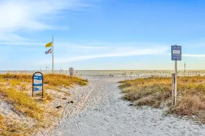 a beach with a flag and signs on the sand at Beachview studio with full kitchen shared pool and beach access in Santa Rosa Beach