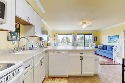 a kitchen with white cabinets and a blue couch at Beachview studio with full kitchen shared pool and beach access in Santa Rosa Beach