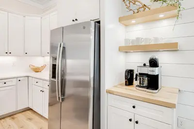 a kitchen with white cabinets and a stainless steel refrigerator at Dog-friendly home with community pool flat top grill and custom coffee bar in Rosemary Beach