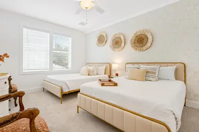 two beds in a bedroom with two windows at Dog-friendly home with community pool flat top grill and custom coffee bar in Rosemary Beach