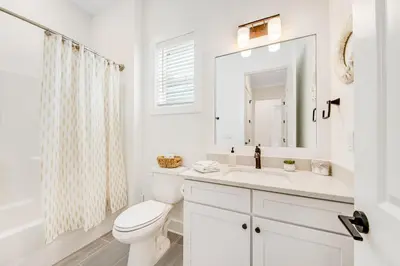 a white bathroom with a toilet and a sink at Dog-friendly home with community pool flat top grill and custom coffee bar in Rosemary Beach