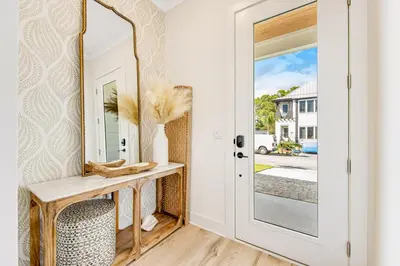 a hallway with a mirror and a table with a chair at Dog-friendly home with community pool flat top grill and custom coffee bar in Rosemary Beach
