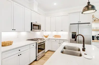 a white kitchen with white cabinets and a sink at Dog-friendly home with community pool flat top grill and custom coffee bar in Rosemary Beach