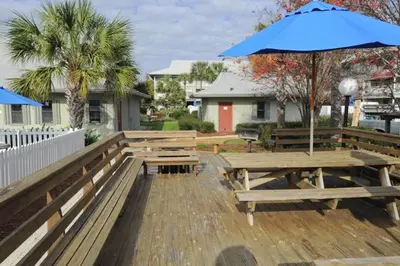 a picnic table with an umbrella on a deck at Cute ground floor condo with shared pool access to shuffleboard and tennis in Santa Rosa Beach
