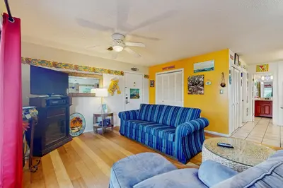 a living room with a blue couch and a tv at Cute ground floor condo with shared pool access to shuffleboard and tennis in Santa Rosa Beach
