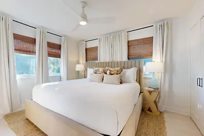 a white bedroom with a large bed with windows at Courtyard view condo with private beach access private balcony & free WiFi in Santa Rosa Beach