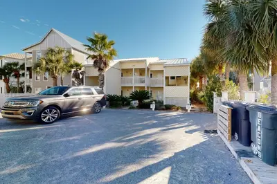 a car parked in a parking lot in front of a house at Courtyard view condo with private beach access private balcony & free WiFi in Santa Rosa Beach
