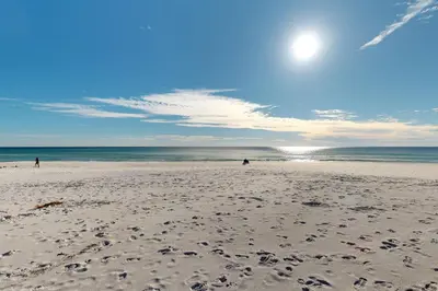 a beach with people walking on the sand and the ocean at Courtyard view condo with private beach access private balcony & free WiFi in Santa Rosa Beach