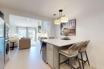 a kitchen with a counter and chairs in a room at Courtyard view condo with private beach access private balcony & free WiFi in Santa Rosa Beach