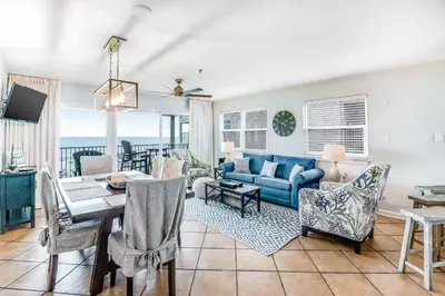 a dining room and living room with a blue couch at Oceanfront condo with pool access washer&dryer central AC and ocean view in Santa Rosa Beach