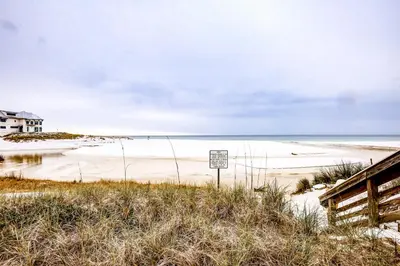 a beach with a sign in front of the ocean at Picturesque gulf-front condo on 30A Steps to beach Charcoal grills on-site in Santa Rosa Beach