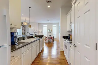 a kitchen with white cabinets and a wooden floor at Colorful house near the beach with shared swimming pool in Santa Rosa Beach