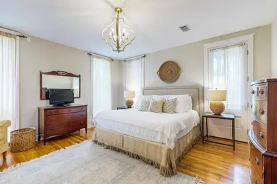 a bedroom with a bed and a television and a chandelier at Colorful house near the beach with shared swimming pool in Santa Rosa Beach