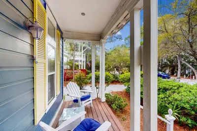 a porch with two white chairs on a blue house at Colorful house near the beach with shared swimming pool in Santa Rosa Beach
