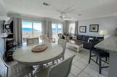 a kitchen and living room with a table and chairs at Lovely first floor condo with ocean views patio & grill - steps from the beach in Santa Rosa Beach