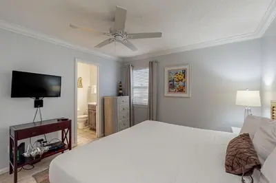 a bedroom with a white bed and a flat screen tv at Lovely first floor condo with ocean views patio & grill - steps from the beach in Santa Rosa Beach