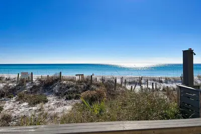 a view of a beach with a bench and the ocean at Lovely first floor condo with ocean views patio & grill - steps from the beach in Santa Rosa Beach