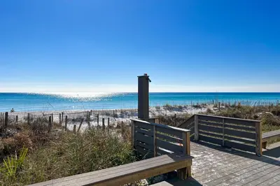 a bench sitting on a walkway to the beach at Lovely first floor condo with ocean views patio & grill - steps from the beach in Santa Rosa Beach