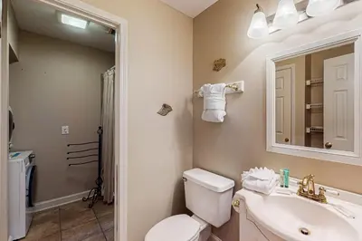 a bathroom with a toilet and a sink and a mirror at Charming gulf-front 2nd floor condo in South Walton Outdoor showers on-site in Santa Rosa Beach