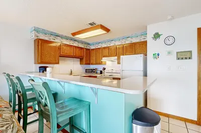 a kitchen with wooden cabinets and a white refrigerator at 1st floor gulf front condo with amazing views charcoal grills - walk to the beach in Santa Rosa Beach
