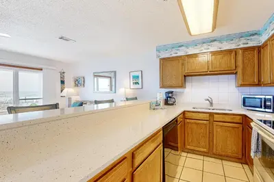 a kitchen with wooden cabinets and a counter top at 1st floor gulf front condo with amazing views charcoal grills - walk to the beach in Santa Rosa Beach