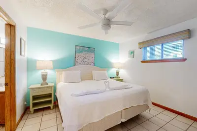a bedroom with a bed with white sheets and a ceiling fan at 1st floor gulf front condo with amazing views charcoal grills - walk to the beach in Santa Rosa Beach