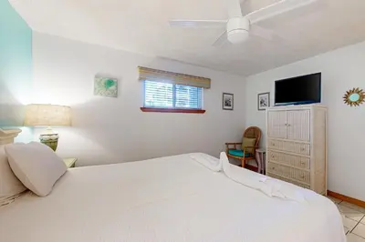 a bedroom with a white bed and a flat screen tv at 1st floor gulf front condo with amazing views charcoal grills - walk to the beach in Santa Rosa Beach